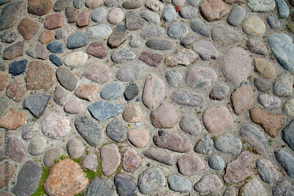Ancient paving stones. The cobblestones of the ancient city. Natural surface roads. Background and texture of the stones. Round stones of the street. Ancient paving stones. The cobblestones of the ancient city. Natural surface roads. Background and texture of the stones. Round stones of the street.