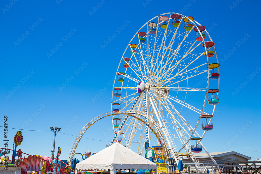 © powerbeephoto - Giant ferris wheel in Amusement park with blue sky background