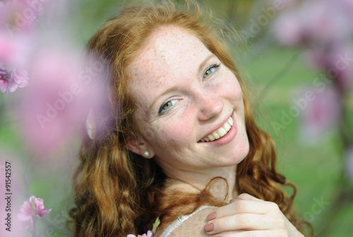 beautiful red-haired girl among the flowering trees