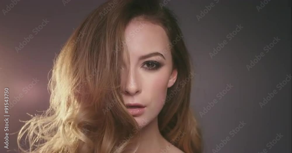 Sexy woman fashion spinning around hair in slow motion on dark background with moody lighting Sexy woman fashion spinning around hair in slow motion on dark background with moody lighting