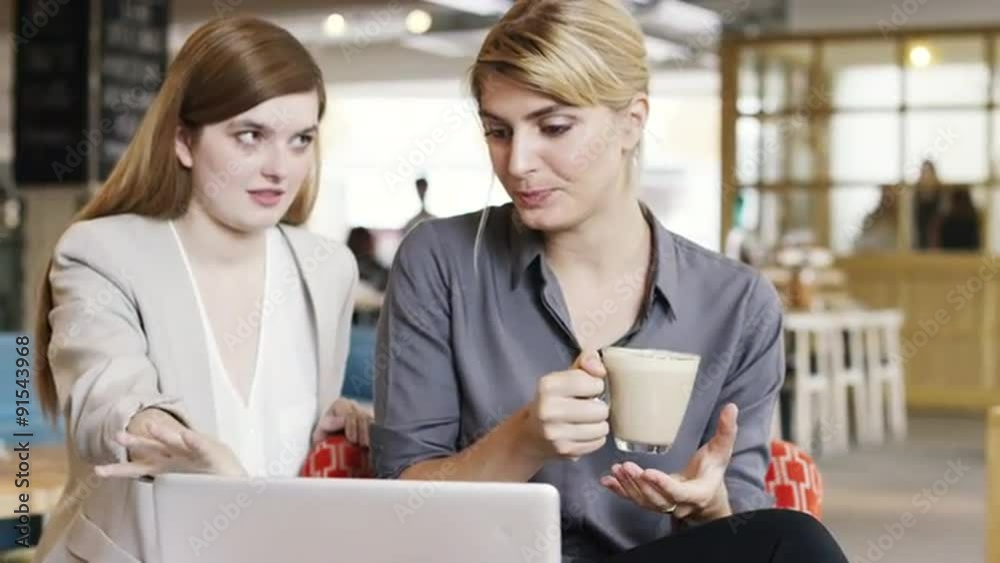 Business women meeting in cafe using laptop drinking coffee Business women meeting in cafe using laptop drinking coffee