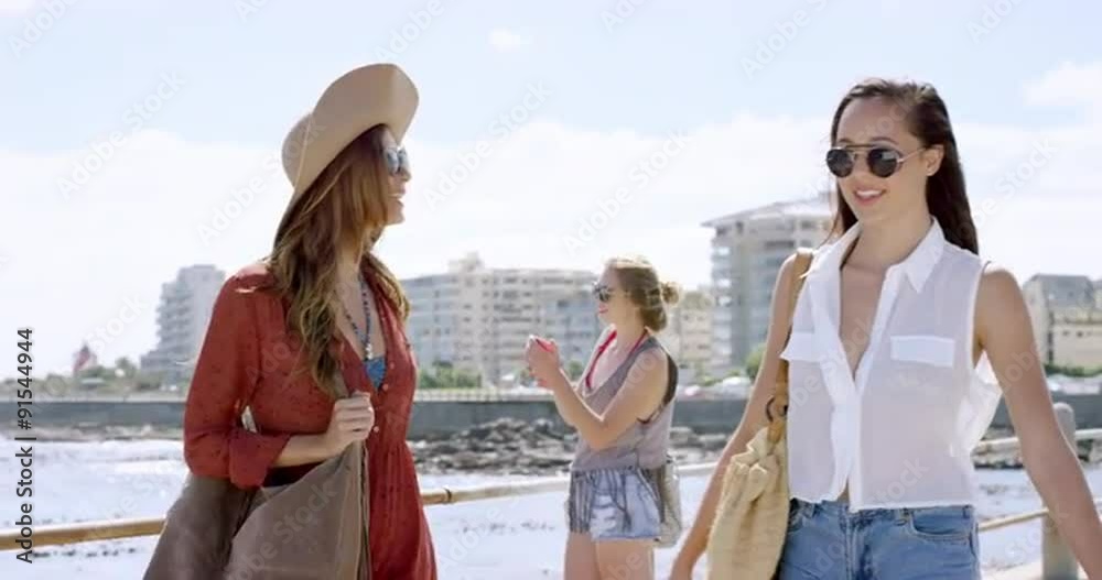 Three young women tourists on summer vacation walking on beach promenade Three young women tourists on summer vacation walking on beach promenade