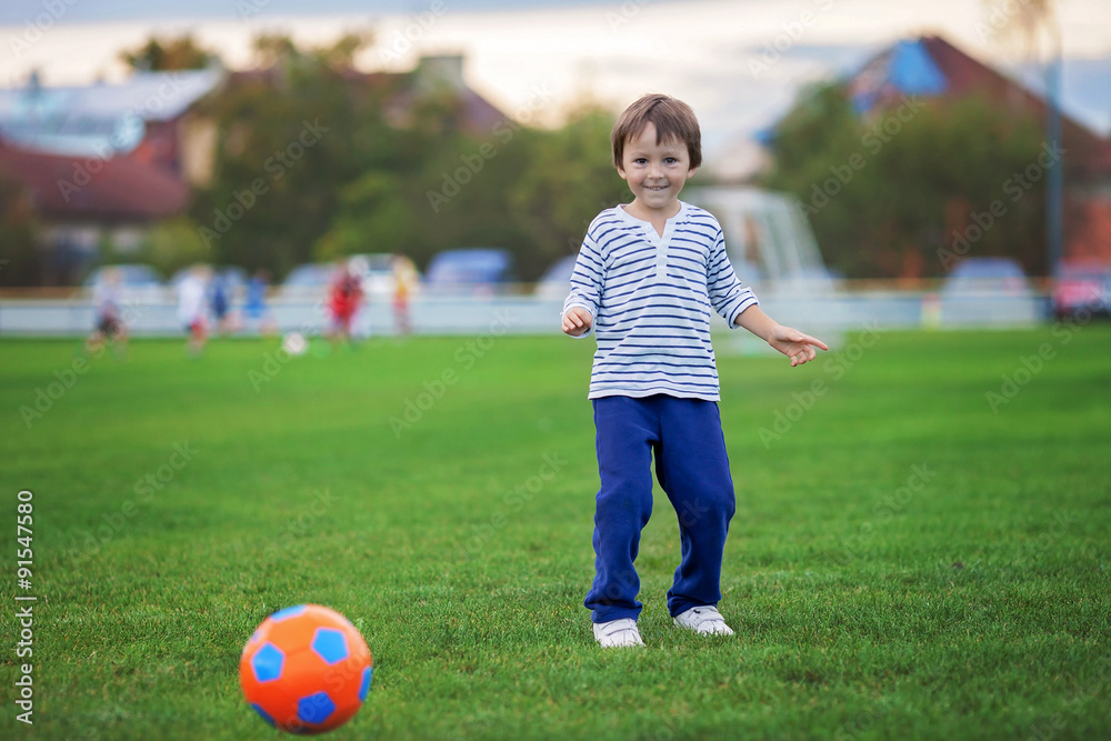 Little toddler boy playing soccer and football, having fun outdo