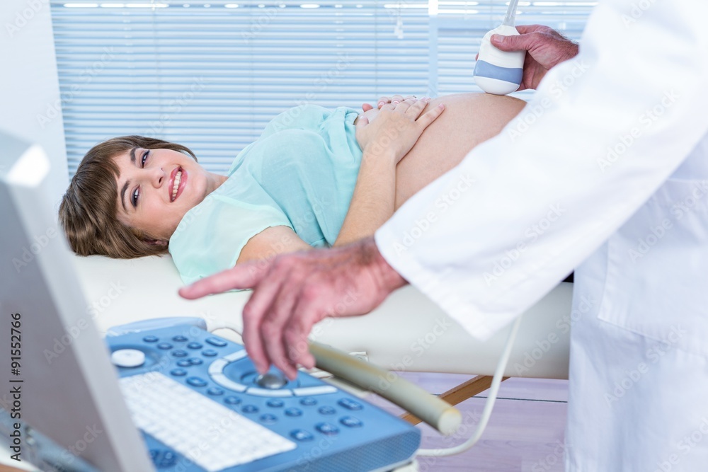 Obraz premium Doctor showing ultrasound monitor to happy pregnant woman