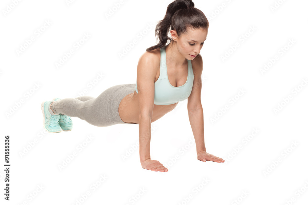 athletic woman doing push-ups on a white background. Fitness model with a beautiful, athletic body athletic woman doing push-ups on a white background. Fitness model with a beautiful, athletic body
