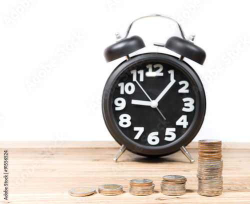 Antique clock and coins on wooden table on white background