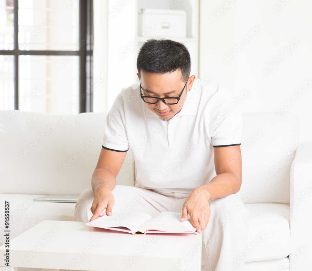 casual asian man reading in livingroom casual asian man reading in livingroom