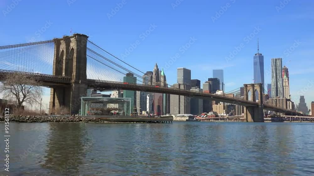 Water level establishing shot of New York City financial district with Brooklyn Bridge foreground and boats passing under. Water level establishing shot of New York City financial district with Brooklyn Bridge foreground and boats passing under.