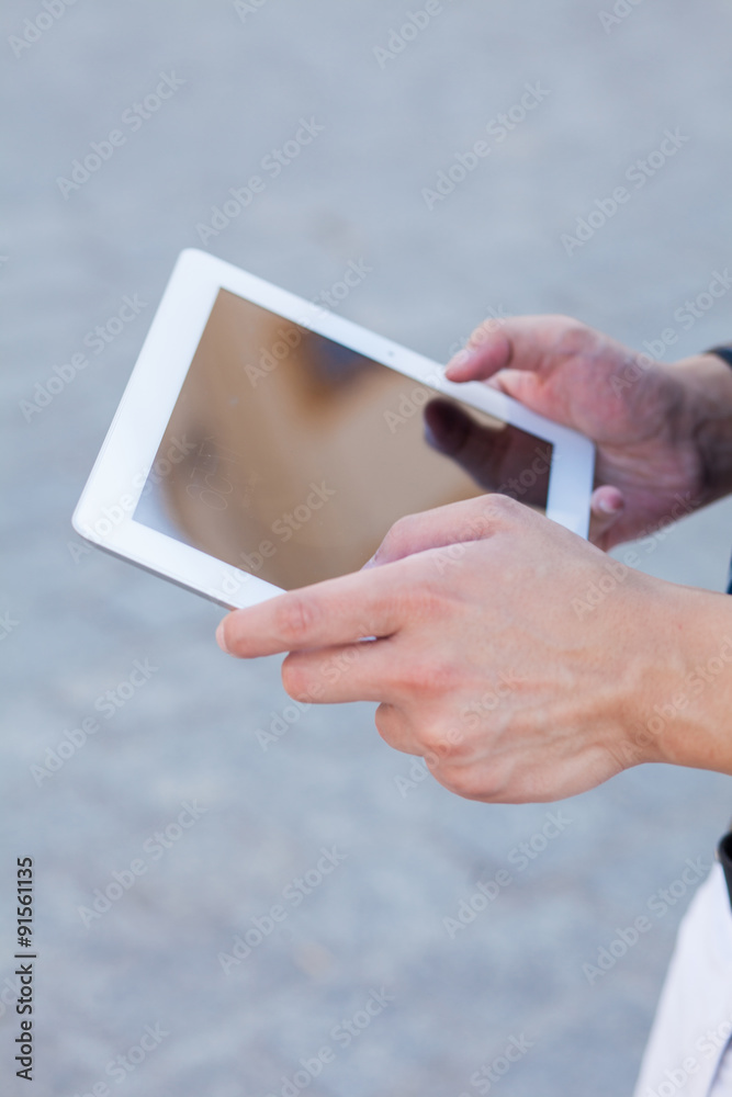 Male hand touching digital tablet pc. Outside photo.