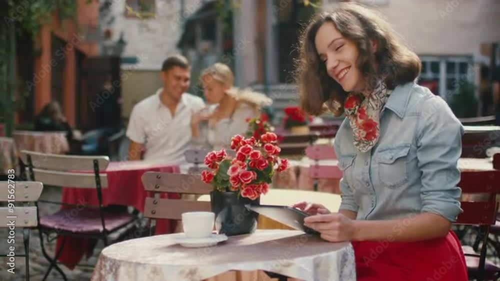 Smiling Girl is Using Tablet in Outdoor Coffee Shop Smiling Girl is Using Tablet in Outdoor Coffee Shop