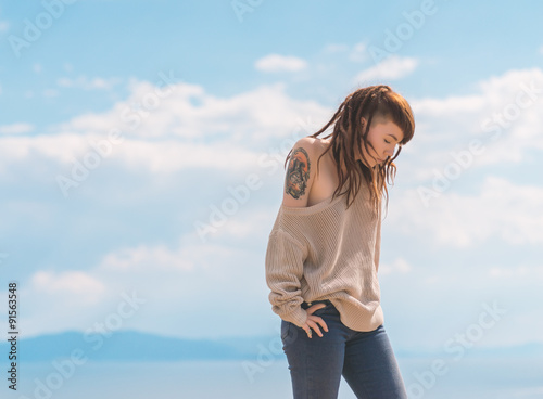 Young asian woman dancing over blue sky background.