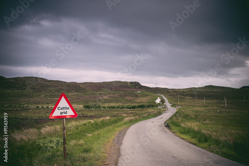 Road in the fields, dark cloudy sky. Isle of Skye, Scotland