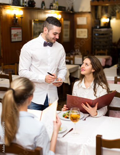 Waiter servicing visitors in restaurant