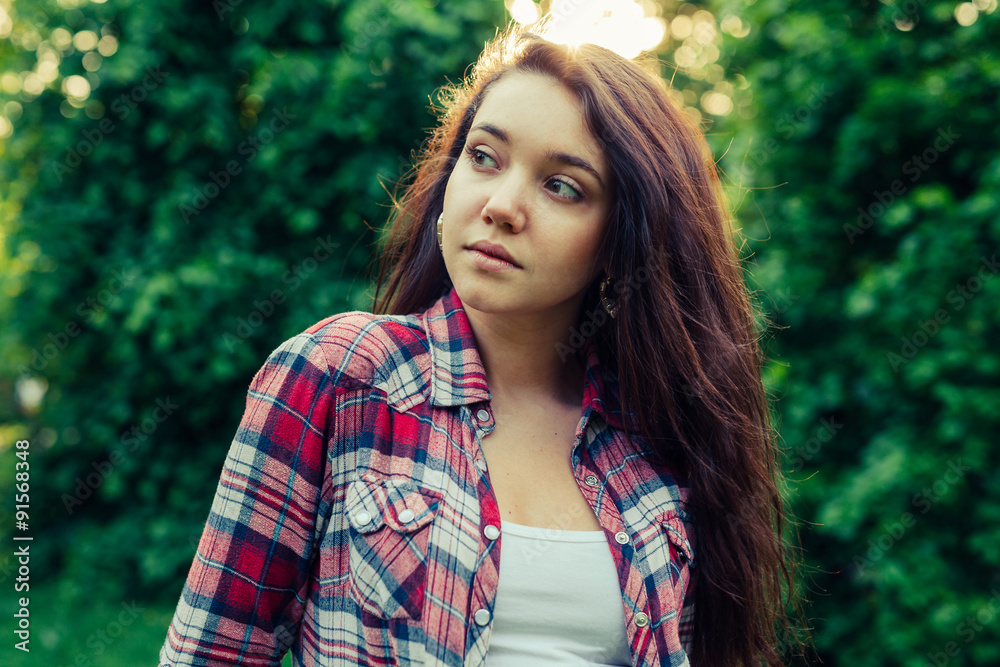 Brown hair girl sitting on the grass in the park and posing to the picture. Brown hair girl sitting on the grass in the park and posing to the picture.