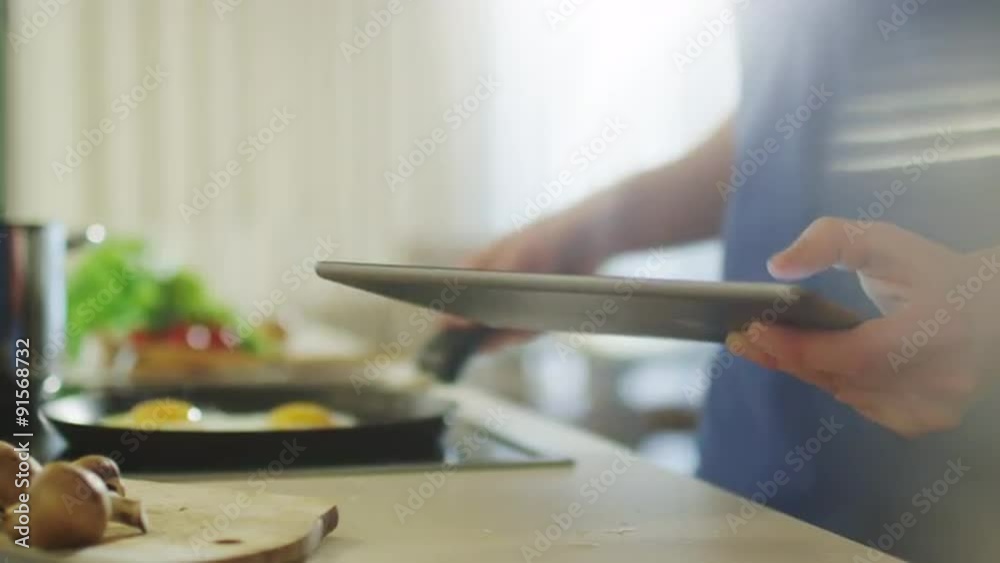 Man is Using Tablet PC While Preparing Food Man is Using Tablet PC While Preparing Food