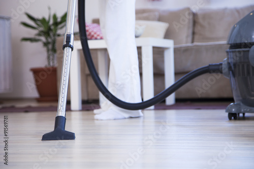 Woman with Vacuum Cleaner. Woman using vacuum cleaner at home in the living room