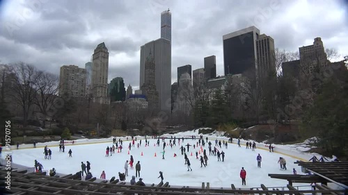 Amazing tie lapse shot of Ice skaters in Central Park, New York City moving at normal speed while sky moves in time lapse.