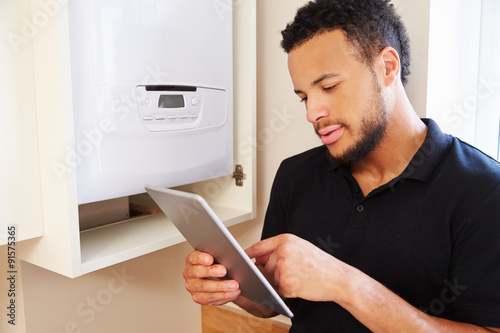 Technician servicing boiler using tablet computer
