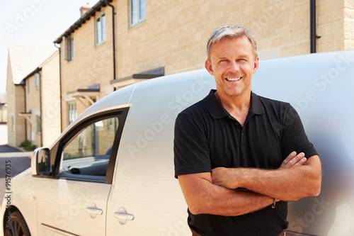 Portrait of middle aged tradesman standing by his van photo