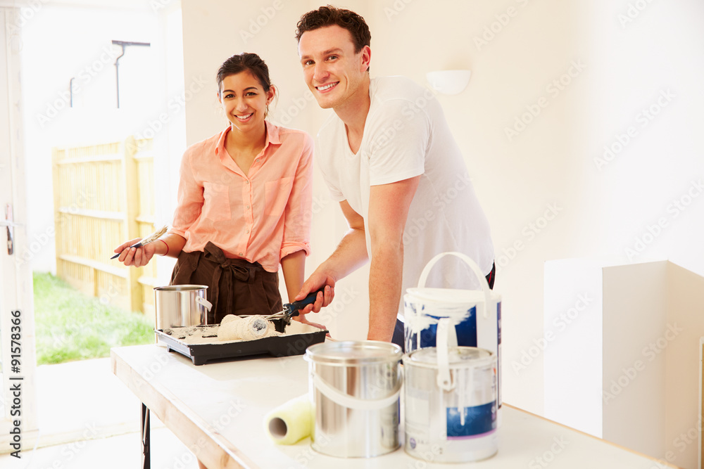 Young couple decorating a room, looking to camera Young couple decorating a room, looking to camera