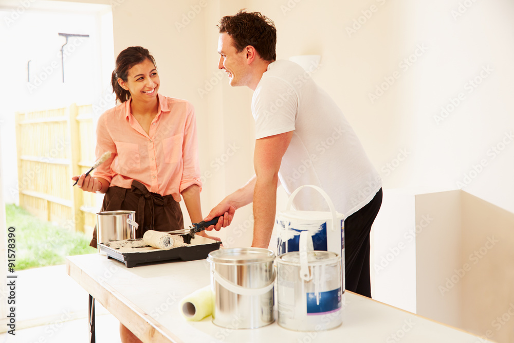 Young couple decorating a room looking at each other Young couple decorating a room looking at each other