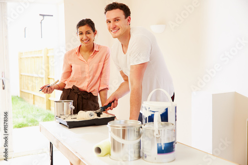 Young couple decorating a room, looking to camera