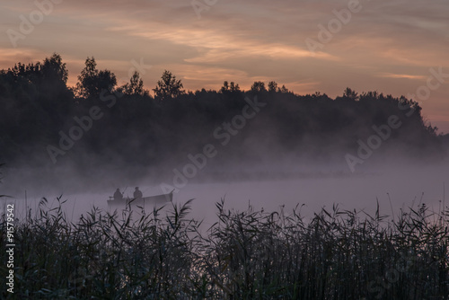 Anonymous fishermen in the morning fog on a lake