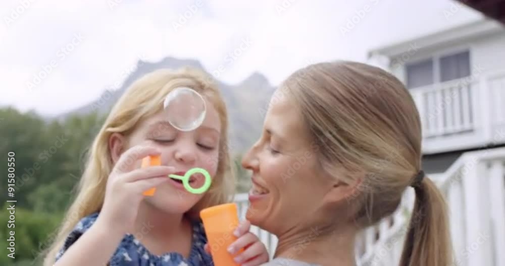 Mother and Daughter blowing bubbles in the yard happy family home Mother and Daughter blowing bubbles in the yard happy family home