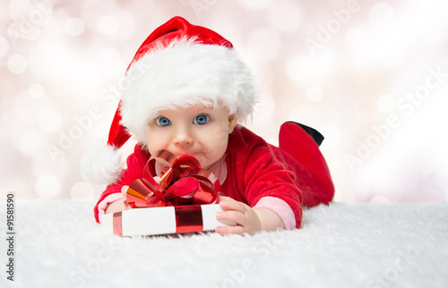 Beautiful little baby celebrates Christmas. New Year's holidays. Baby in a Christmas costume with gift
