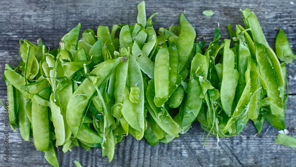 Bunch of opened pods from green peas lying on wooden surface Bunch of opened pods from green peas lying on wooden surface