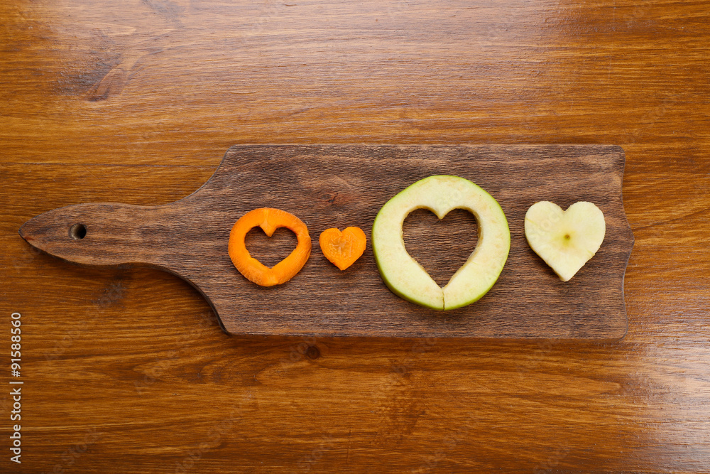Fruits slices with cut in shape of heart on wooden background Fruits slices with cut in shape of heart on wooden background