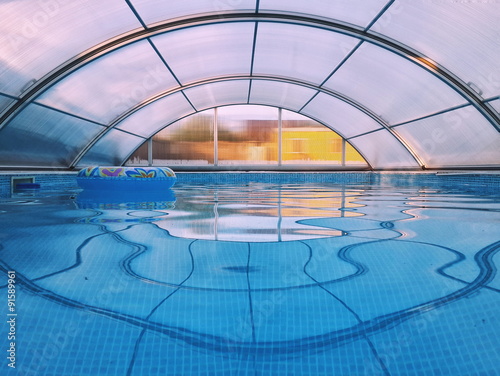 Indoor swimming pool with blue water covered by transparent dome structure