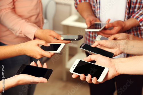 Many hands holding mobile phones close up