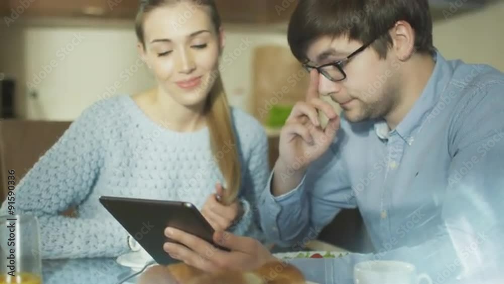 Couple is Using Tablet at Home in Kitchen Couple is Using Tablet at Home in Kitchen