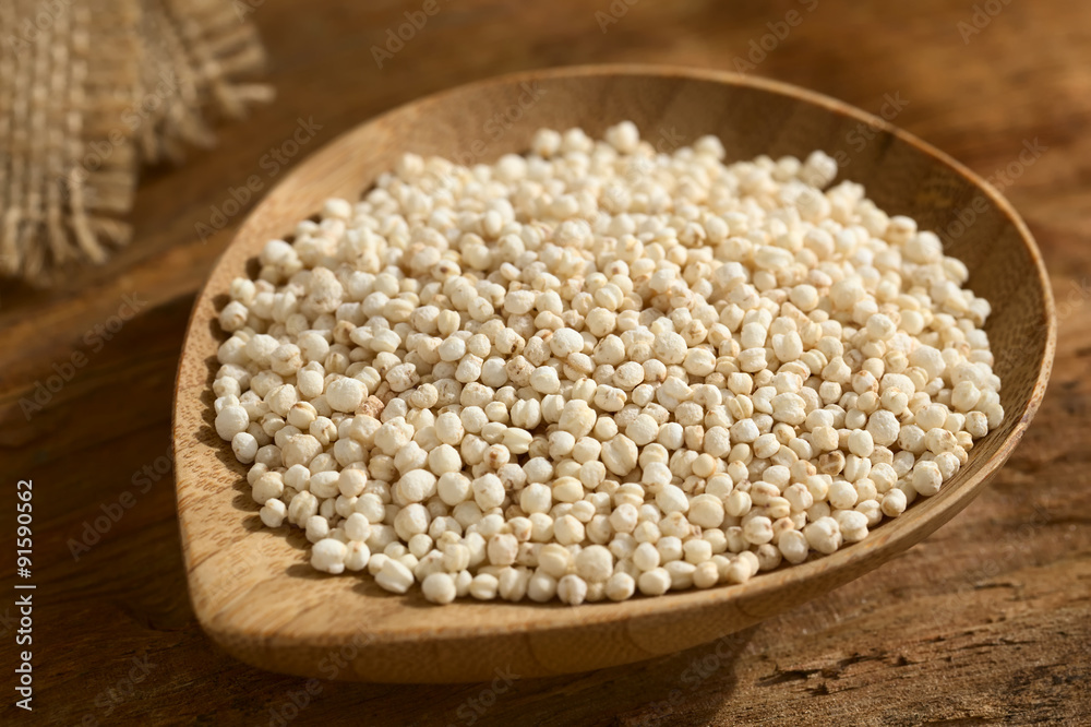 Popped white quinoa (lat. Chenopodium quinoa) cereal on small wooden plate, photographed on wood with natural light (Selective Focus, Focus one third into the quinoa cereal) Popped white quinoa (lat. Chenopodium quinoa) cereal on small wooden plate, photographed on wood with natural light (Selective Focus, Focus one third into the quinoa cereal)
