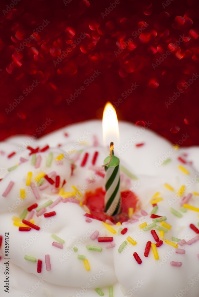 Cupcake with a lit candle over bright red background Cupcake with a lit candle over bright red background