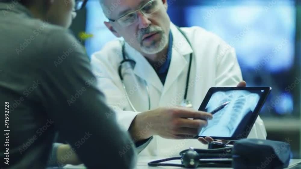 Doctor is Shows X-ray Images to Patient on Tablet PC. Doctor is Shows X-ray Images to Patient on Tablet PC.