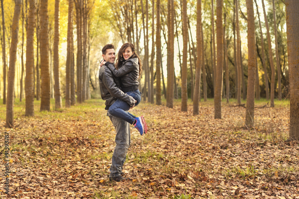 Romantic couple wearing jeans walking in autumn park