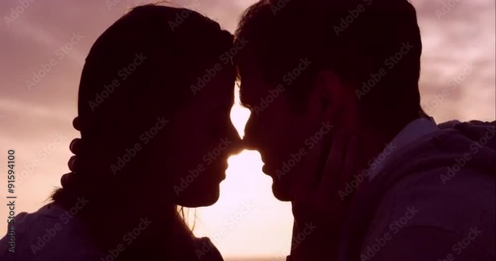 Happy loving couple kissing at sunset showing emotional intimacy touching hugging and cuddling Happy loving couple kissing at sunset showing emotional intimacy touching hugging and cuddling