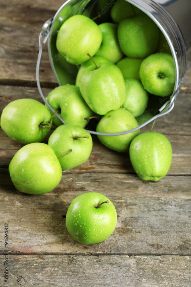 Ripe green apple in metal bucket on wooden table close up Ripe green apple in metal bucket on wooden table close up