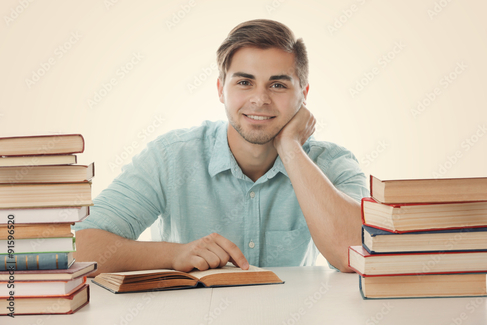 Young man reading book at table on white background Young man reading book at table on white background