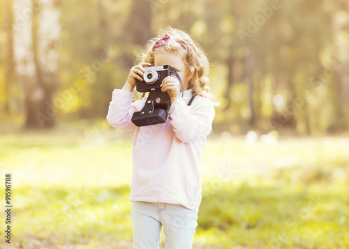 Little child with old retro camera doing photo outdoors