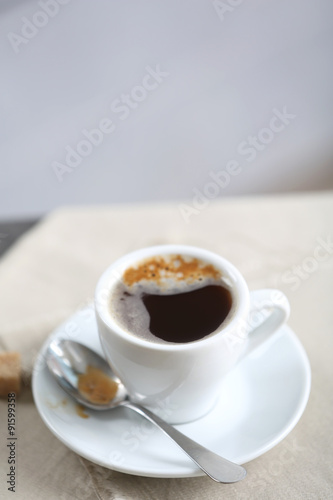 Cup of flavored coffee on table with napkin, closeup