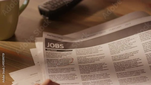 Man Looking for Job in a Newspaper and Marking Advertisement Using Red Pencil
