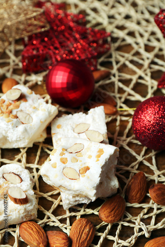 Sweet nougat with almonds and Christmas decoration table close up