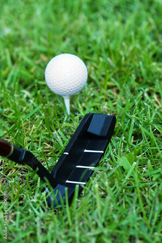 Golf balls and driver on green grass  background