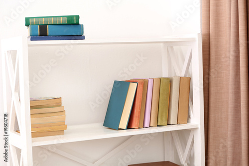 Books on shelves on white wall background © Africa Studio
