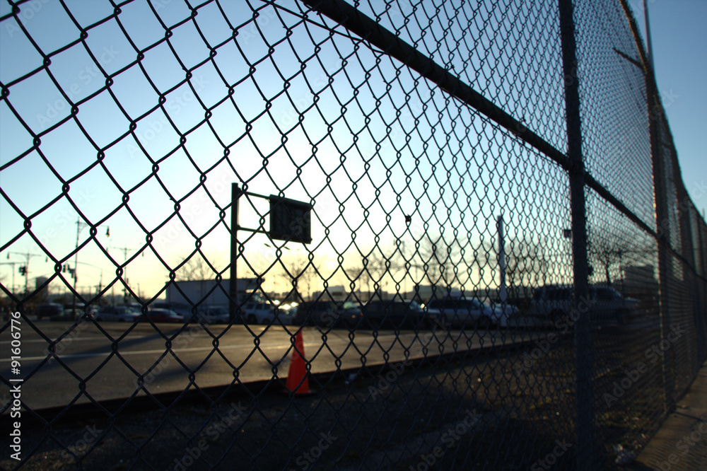 Urban basketball play ground viewed from behind a fence