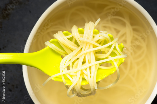 Spoon spaghetti pasta pulls out of the pan with water