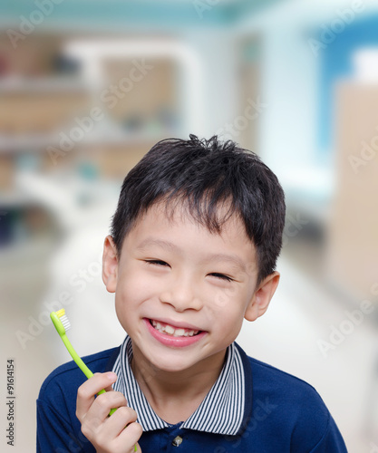 Asian boy holding toothbrush and smiles at dentist clinic